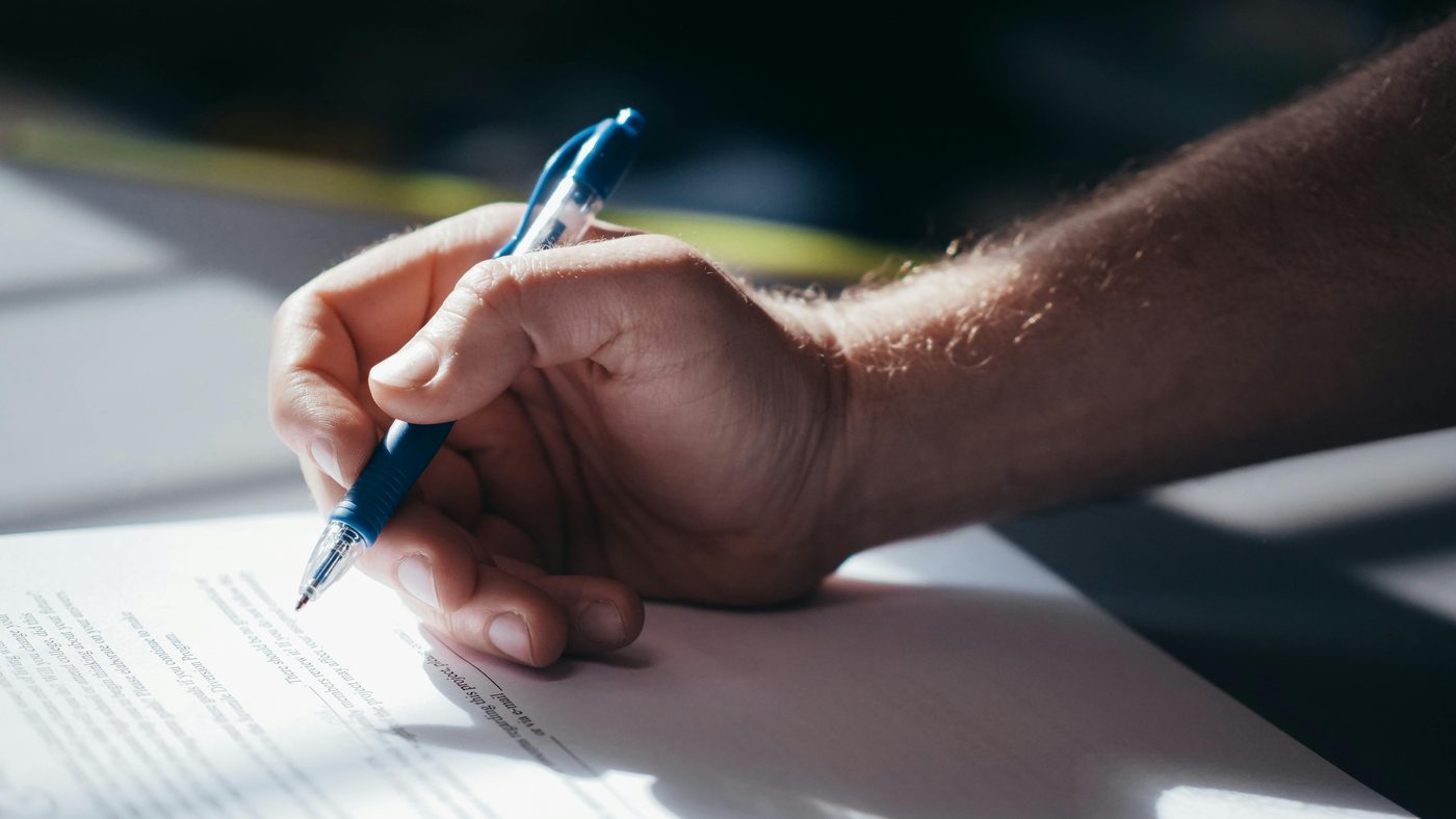 Hand writing a handwritten signature on paper — illustrating a calligraphy-style AI signature